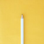 A white pencil against a yellow background