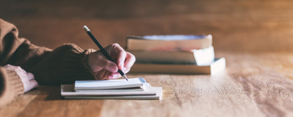 Writing with a notebook and pencil at a wooden table