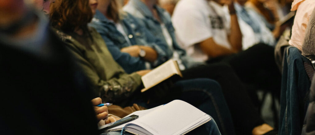 A group of people with open notebooks and pens on their laps