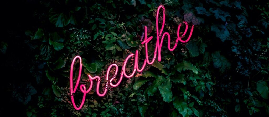 neon pink sign spelling the word BREATHE