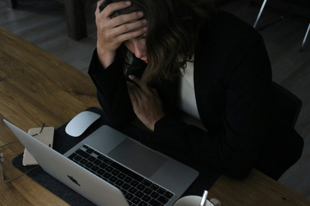 writer with head in hands at laptop