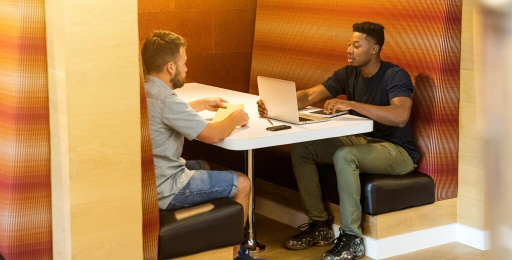 Two writers discuss their work in a coffee shop booth