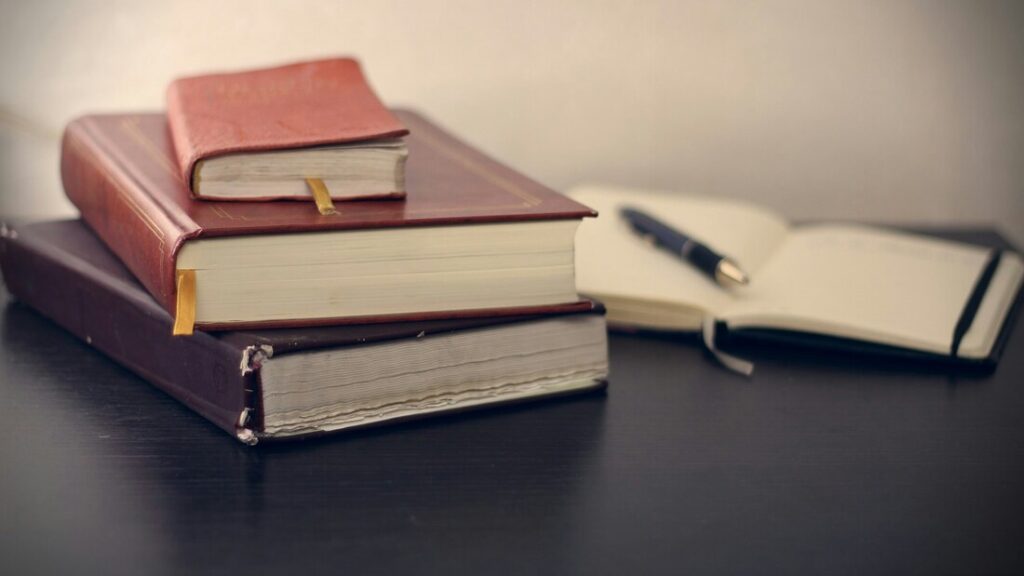 Piled books, notebook and pen