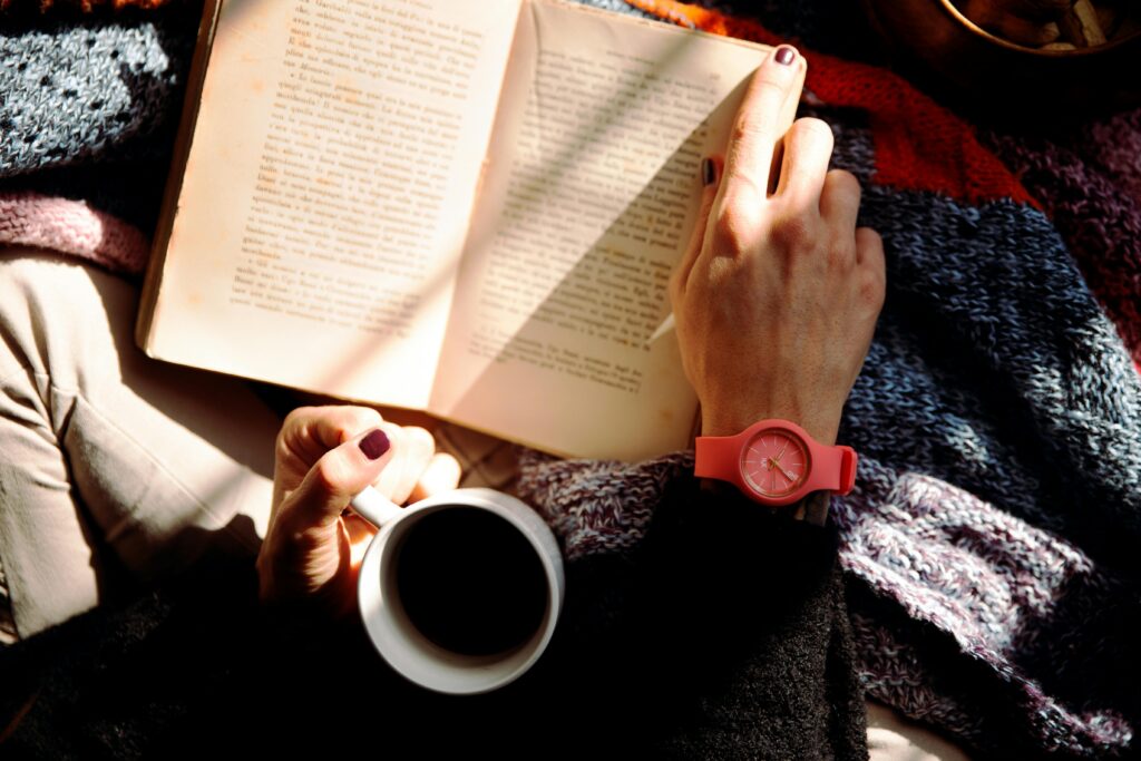A reader with an open book and a cup of coffee