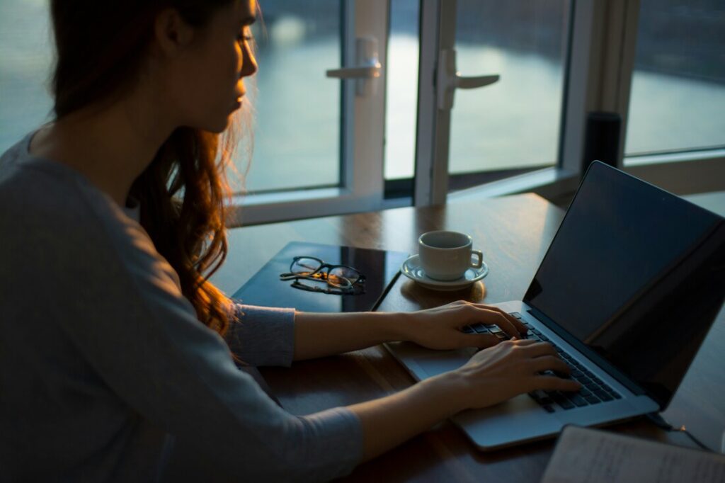 An author types on a laptop in low evening light