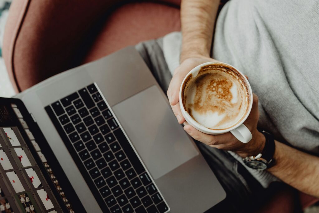 A person relaxing with a latte and laptop, top view on a comfortable chair. Perfect freelance vibe.