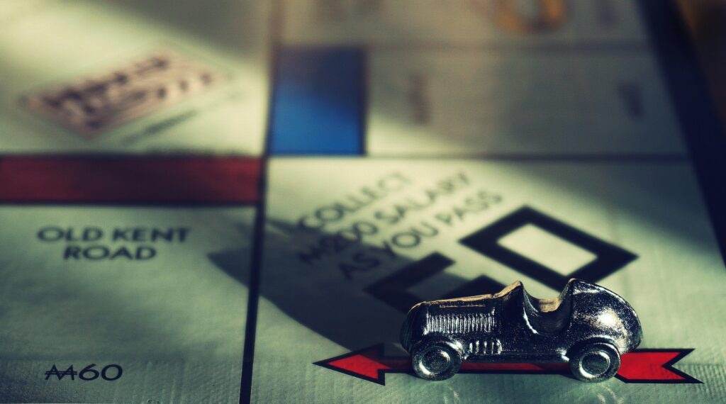 Detailed close-up of Monopoly board featuring the classic car token representing character growth