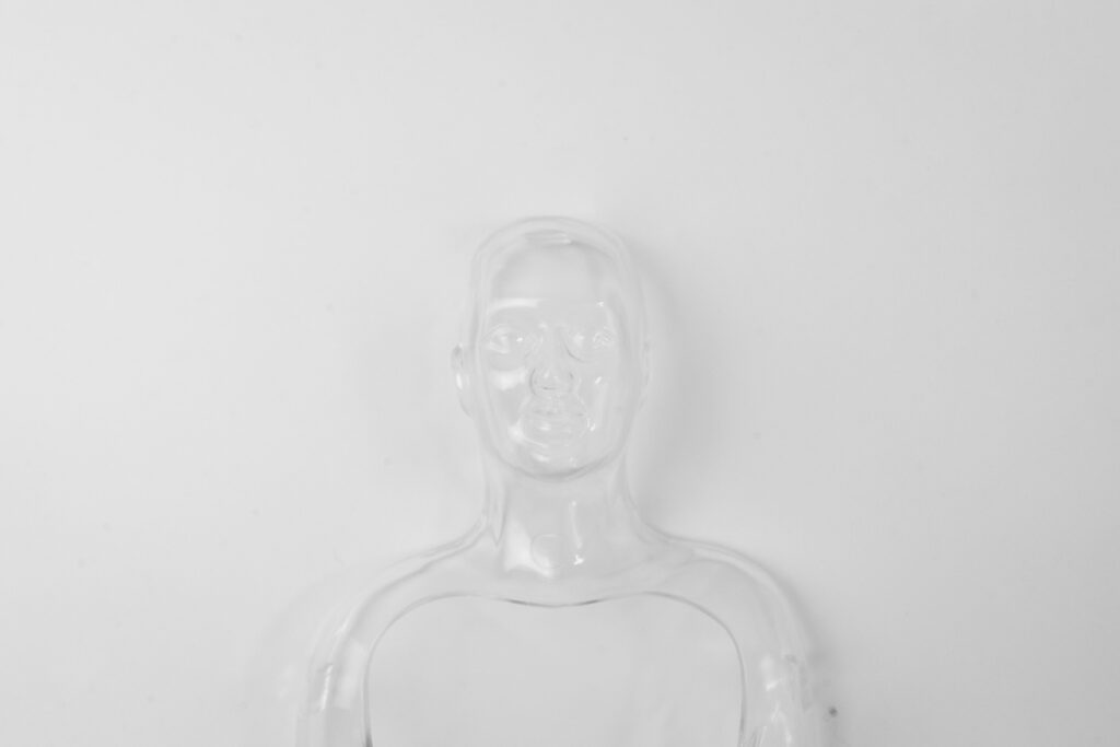 A clear glass figurine on a white backdrop showcasing visible and invisible narratives via character development