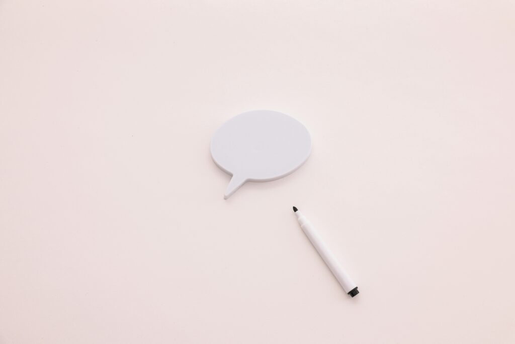 A minimalist speech bubble with a white marker on a clean white background, perfect for creative designs.
