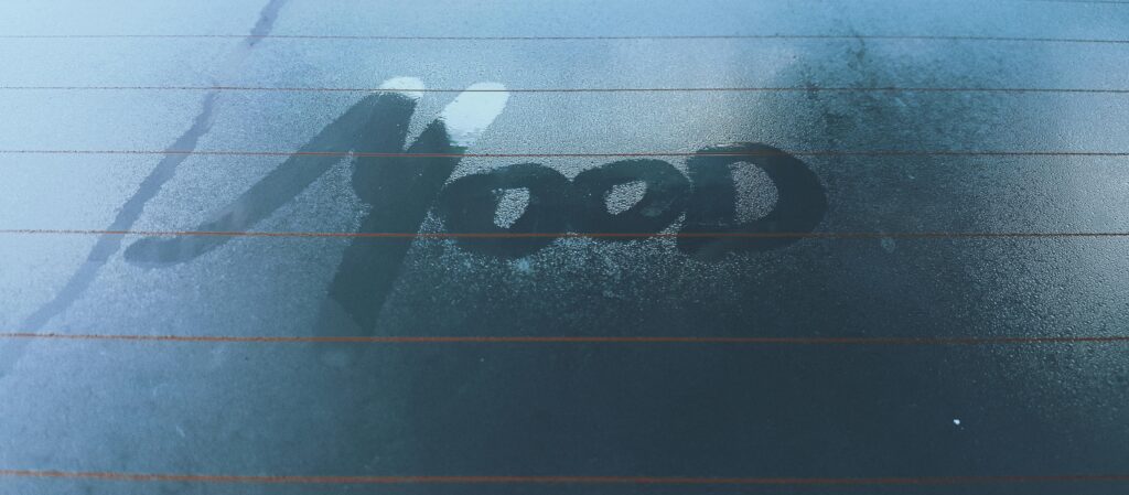 Moist car window with 'mood' written in fog, evoking a contemplative atmosphere.