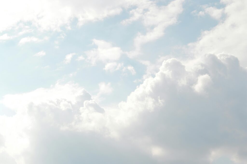 A serene view of thick, fluffy clouds set against a bright blue sky, illustrating the importance of considering and shaping atmosphere in fictional worlds.