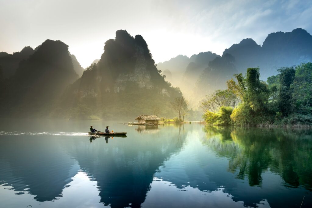 Tranquil lake with mountains reflecting at sunrise in Tuyên Quang, Vietnam.