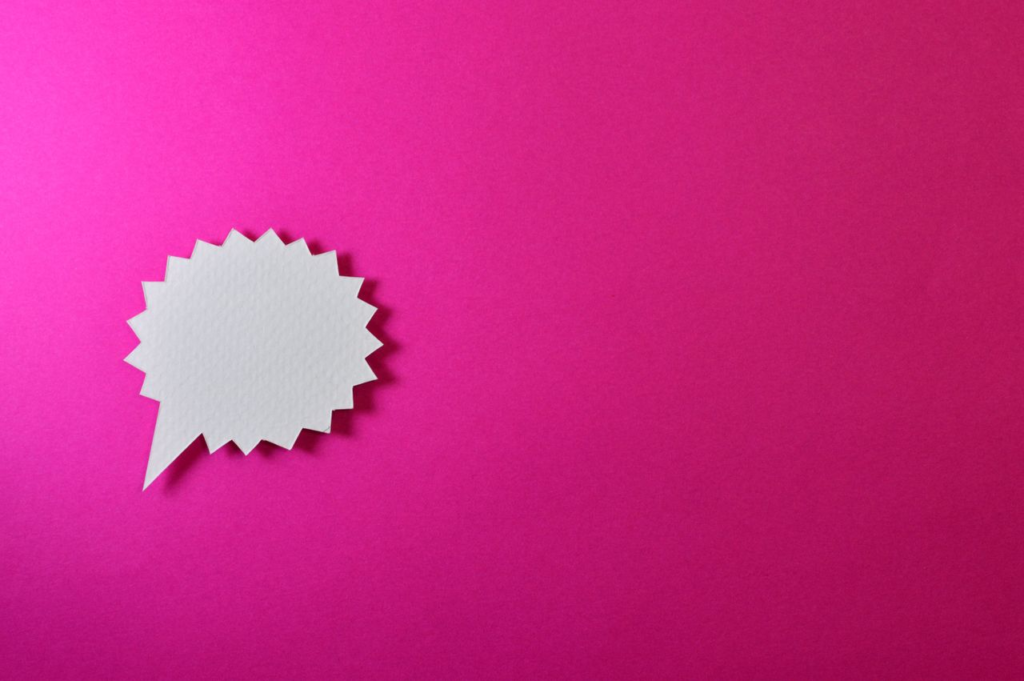 Paper speech bubble on bright pink background with ample copy space.