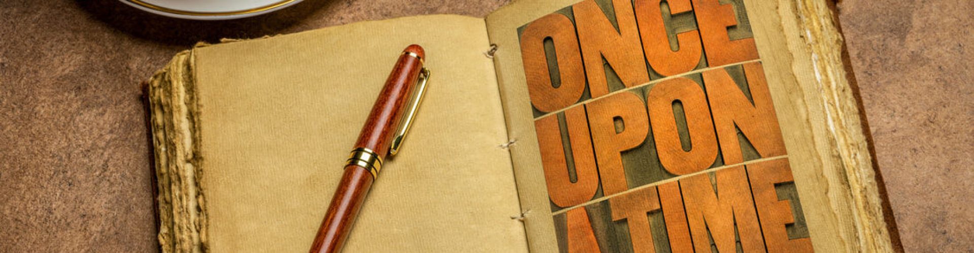 A notebook open on the words ONCE UPON A TIME with a pen ready to start writing